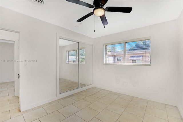 unfurnished bedroom with light tile patterned floors, a closet, and ceiling fan