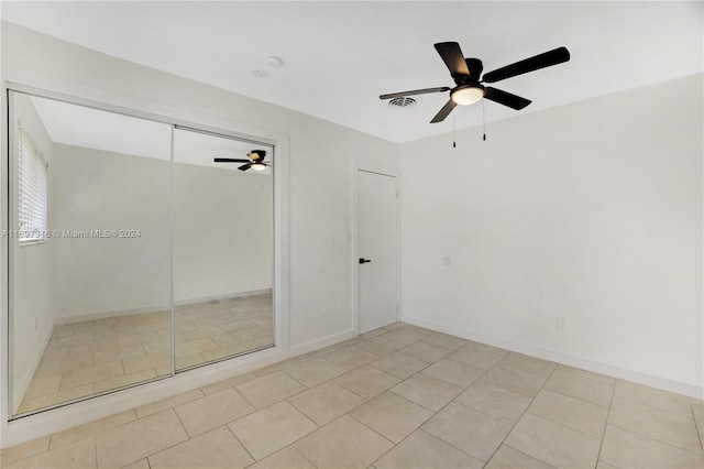 unfurnished bedroom featuring ceiling fan, light tile patterned floors, and a closet