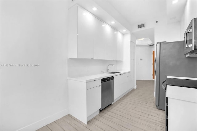 kitchen featuring white cabinets, stainless steel appliances, and light hardwood / wood-style floors