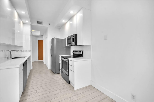 kitchen with white cabinetry, light hardwood / wood-style floors, and appliances with stainless steel finishes