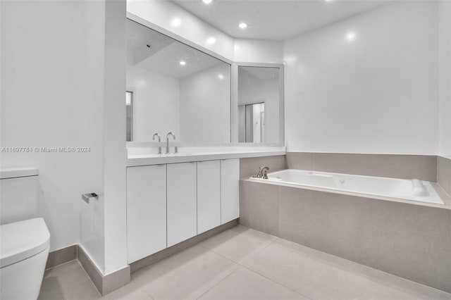 bathroom with tile patterned flooring, vanity, toilet, and tiled tub