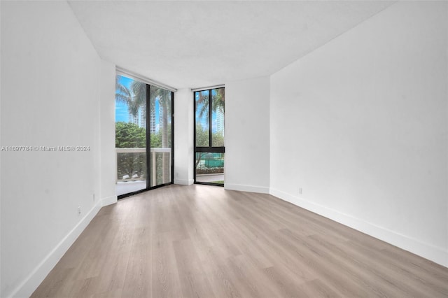 unfurnished room featuring light wood-type flooring and a wall of windows