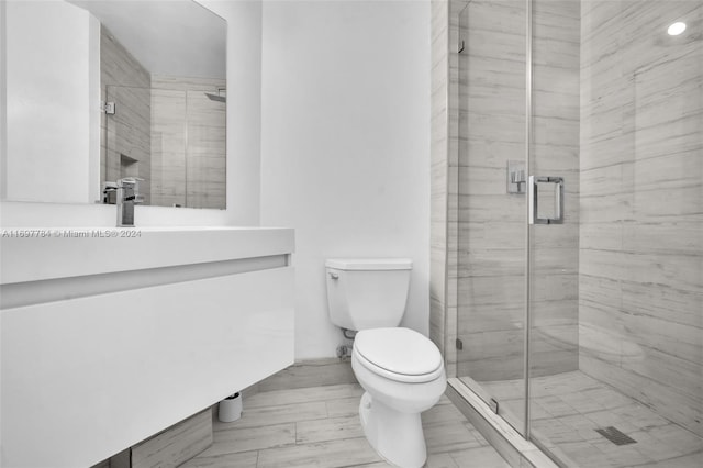 bathroom featuring hardwood / wood-style floors, vanity, an enclosed shower, and toilet