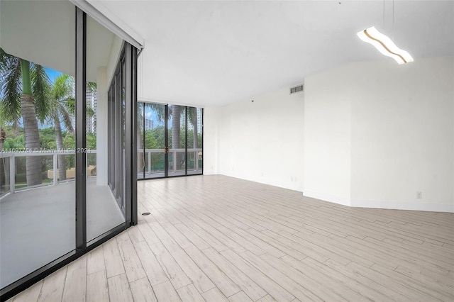 empty room featuring light hardwood / wood-style floors and a wall of windows