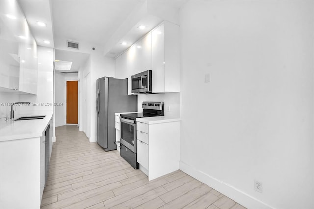 kitchen featuring white cabinets, appliances with stainless steel finishes, light hardwood / wood-style flooring, and sink