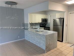 kitchen featuring kitchen peninsula, appliances with stainless steel finishes, decorative backsplash, light tile patterned floors, and white cabinetry