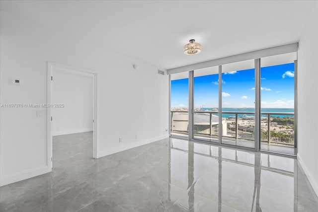 unfurnished room with a healthy amount of sunlight, a wall of windows, and a water view