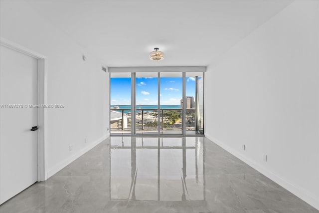 unfurnished room with a water view, a wall of windows, and concrete floors