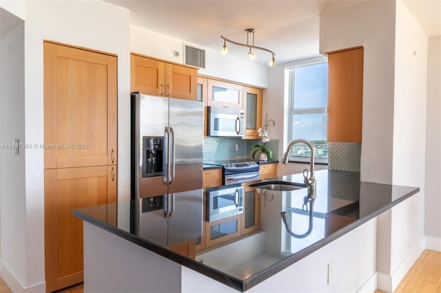 kitchen with kitchen peninsula, decorative backsplash, sink, and appliances with stainless steel finishes