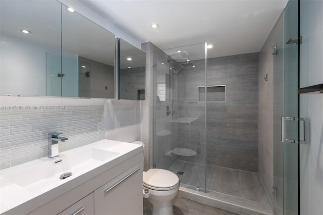 bathroom with vanity, backsplash, toilet, and an enclosed shower