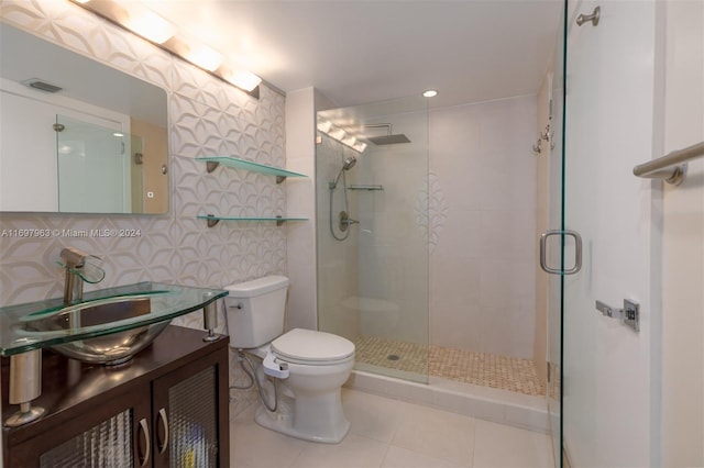 bathroom featuring vanity, a shower with door, tile patterned flooring, decorative backsplash, and toilet