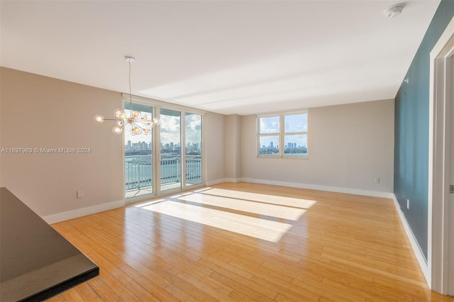 empty room with light wood-type flooring and a chandelier