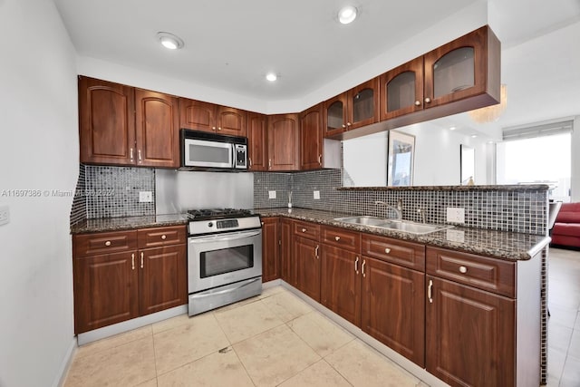 kitchen featuring decorative backsplash, sink, appliances with stainless steel finishes, and dark stone counters