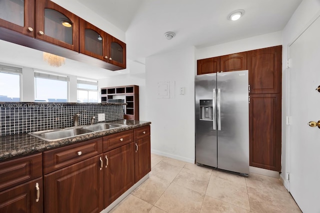 kitchen featuring decorative backsplash, stainless steel fridge with ice dispenser, sink, and dark stone counters