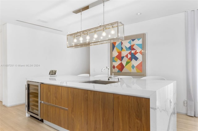 bar featuring pendant lighting, light hardwood / wood-style flooring, wine cooler, and sink