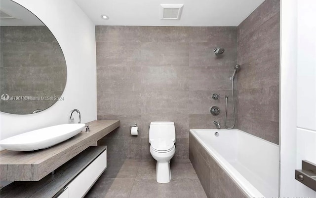 full bathroom with vanity, tile walls, tile patterned flooring, toilet, and tiled shower / bath