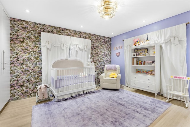 bedroom featuring hardwood / wood-style floors, an inviting chandelier, and a nursery area