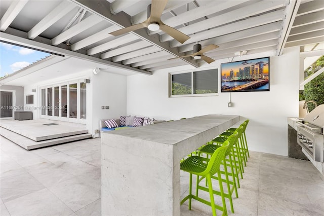 view of patio with ceiling fan, a bar, and exterior kitchen