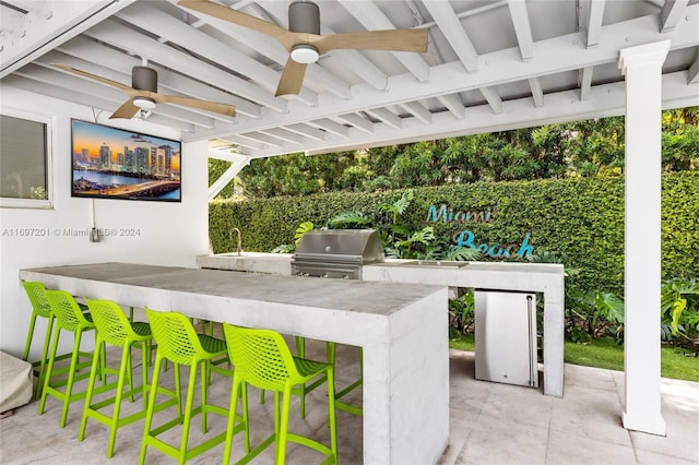 view of patio featuring area for grilling, an outdoor bar, ceiling fan, and a grill