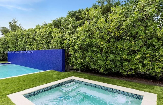 view of swimming pool with a lawn and a jacuzzi