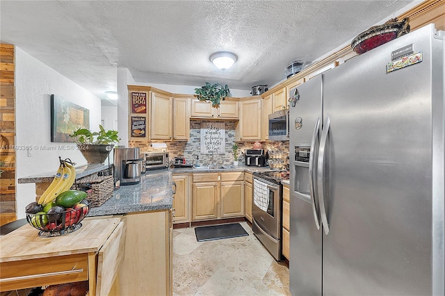 kitchen featuring sink, dark stone countertops, a textured ceiling, light brown cabinetry, and appliances with stainless steel finishes