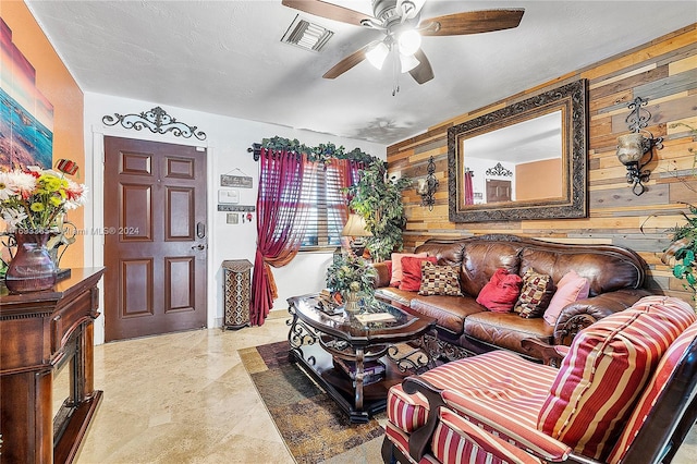 living room featuring wood walls, ceiling fan, and a textured ceiling