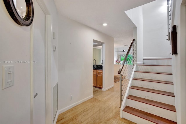 stairway featuring wood-type flooring and sink