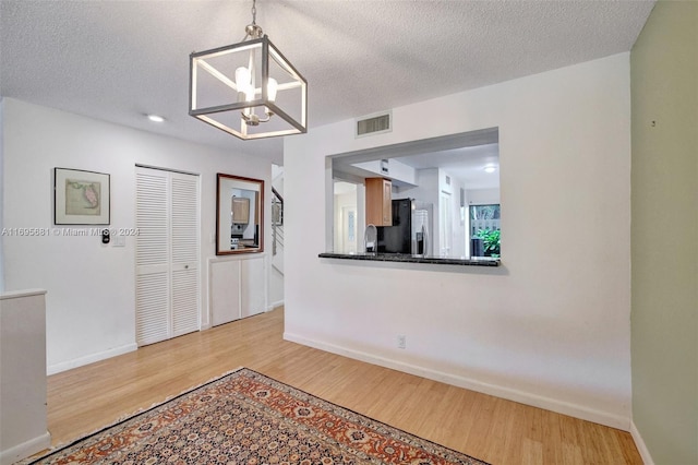 entrance foyer featuring a chandelier, a textured ceiling, and light wood-type flooring