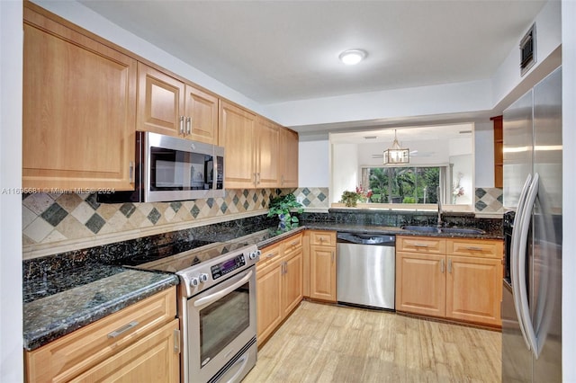 kitchen featuring appliances with stainless steel finishes, tasteful backsplash, sink, light hardwood / wood-style floors, and hanging light fixtures