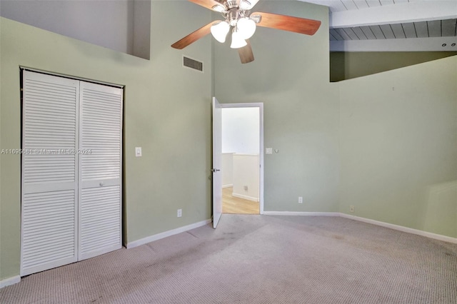 unfurnished bedroom with light carpet, ceiling fan, high vaulted ceiling, beamed ceiling, and a closet