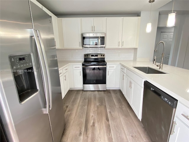 kitchen featuring sink, stainless steel appliances, light hardwood / wood-style flooring, decorative light fixtures, and white cabinets