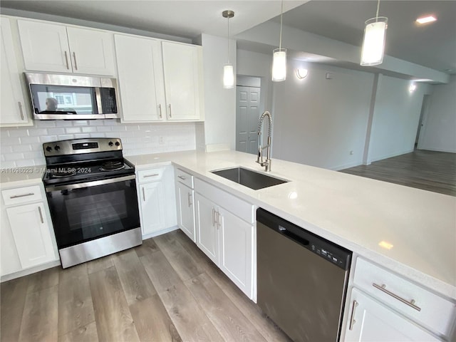 kitchen featuring sink, light hardwood / wood-style flooring, decorative light fixtures, white cabinets, and appliances with stainless steel finishes