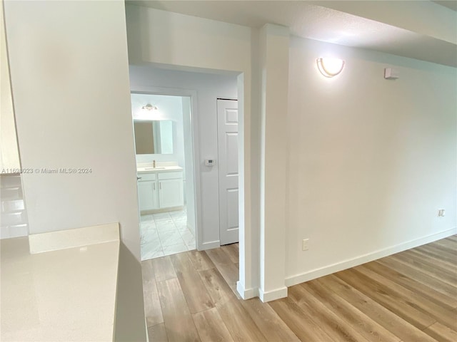 hallway with light wood-type flooring and sink