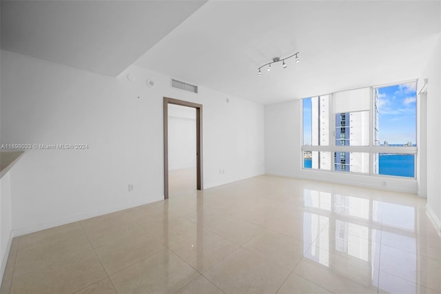 empty room with a water view, track lighting, and light tile patterned floors