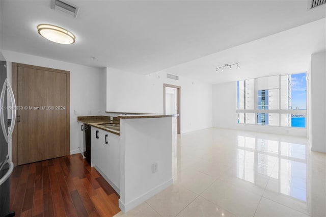 kitchen with kitchen peninsula, light hardwood / wood-style flooring, and black dishwasher