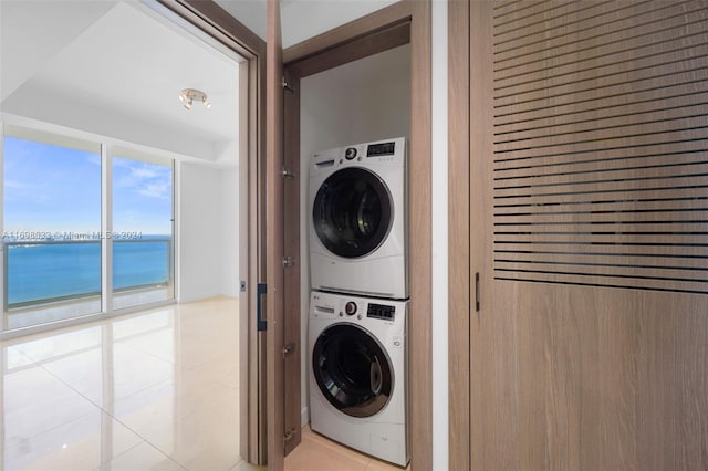 laundry area with a water view, stacked washing maching and dryer, and light tile patterned floors