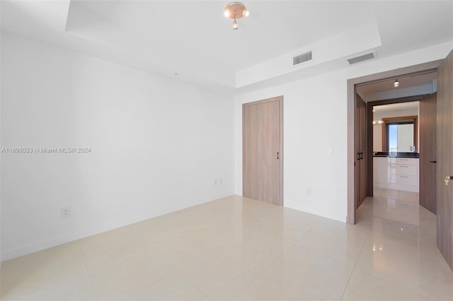 spare room with a tray ceiling and light tile patterned floors