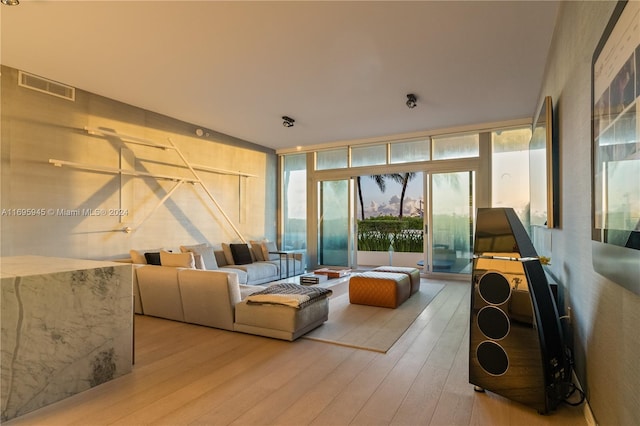 living room featuring light wood-type flooring and a wall of windows