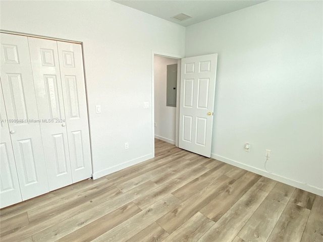 unfurnished bedroom with light hardwood / wood-style floors, electric panel, and a closet