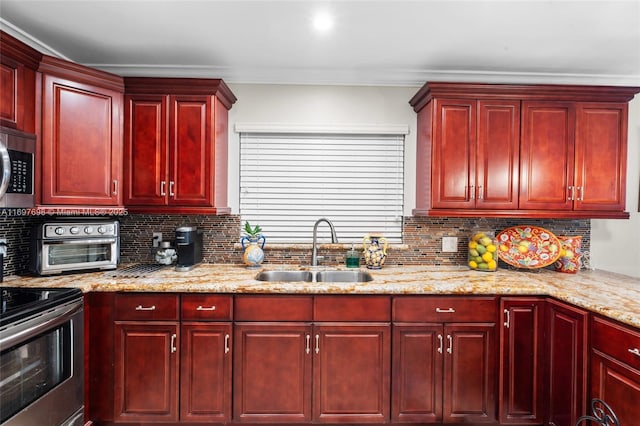 kitchen with backsplash, light stone counters, range, and sink