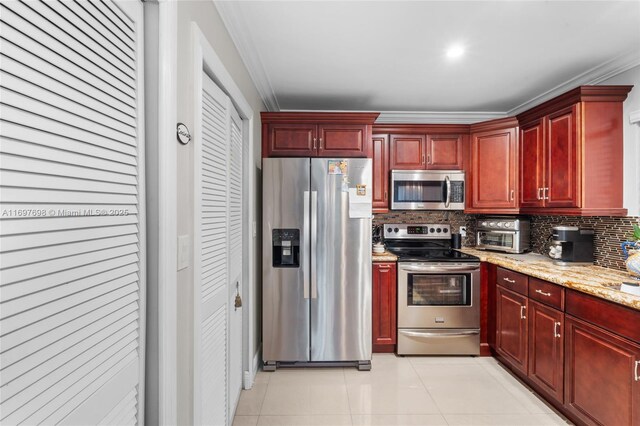 kitchen featuring backsplash, crown molding, light stone countertops, appliances with stainless steel finishes, and light tile patterned flooring