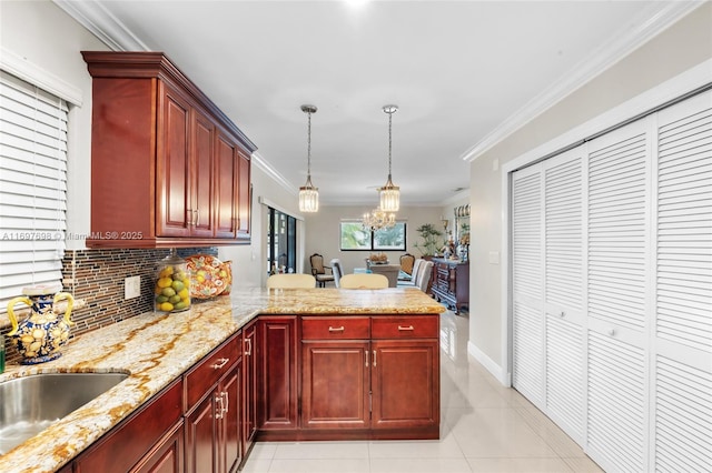 kitchen with sink, hanging light fixtures, kitchen peninsula, crown molding, and light tile patterned floors