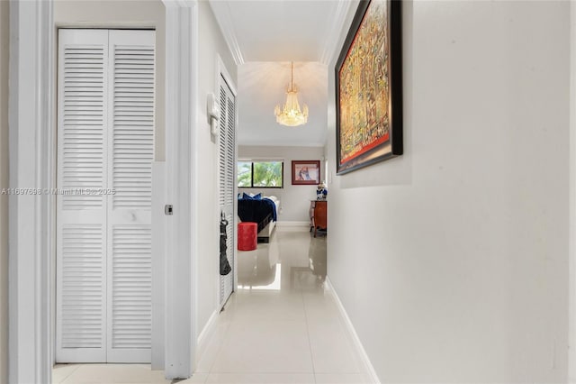 hallway with light tile patterned flooring, a notable chandelier, and ornamental molding