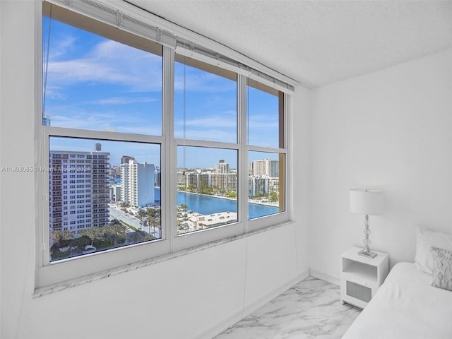 unfurnished bedroom with a textured ceiling, a water view, and a wall of windows