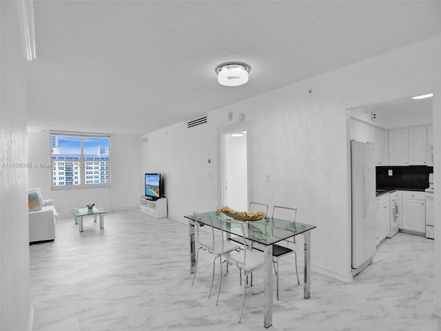 dining space with washer / clothes dryer and a textured ceiling