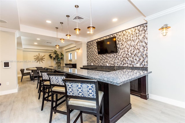 kitchen with light stone countertops, light hardwood / wood-style floors, decorative light fixtures, and ornamental molding