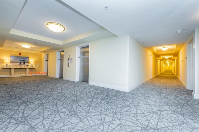 unfurnished room with a tray ceiling and elevator