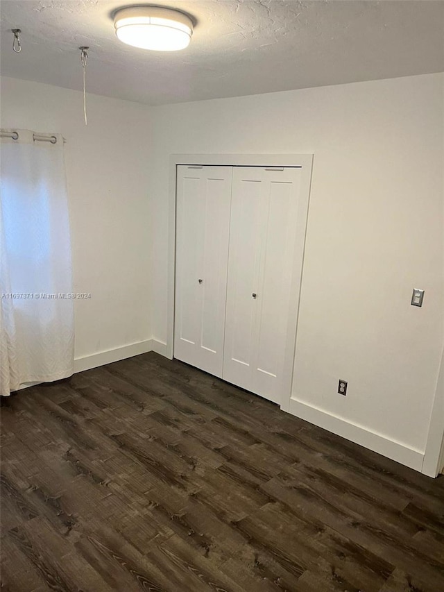 unfurnished bedroom featuring dark hardwood / wood-style flooring and a closet