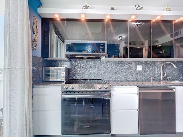 kitchen featuring backsplash, white cabinetry, and appliances with stainless steel finishes