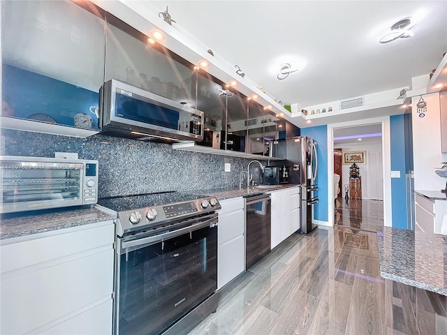 kitchen featuring white cabinets, sink, light hardwood / wood-style flooring, decorative backsplash, and appliances with stainless steel finishes